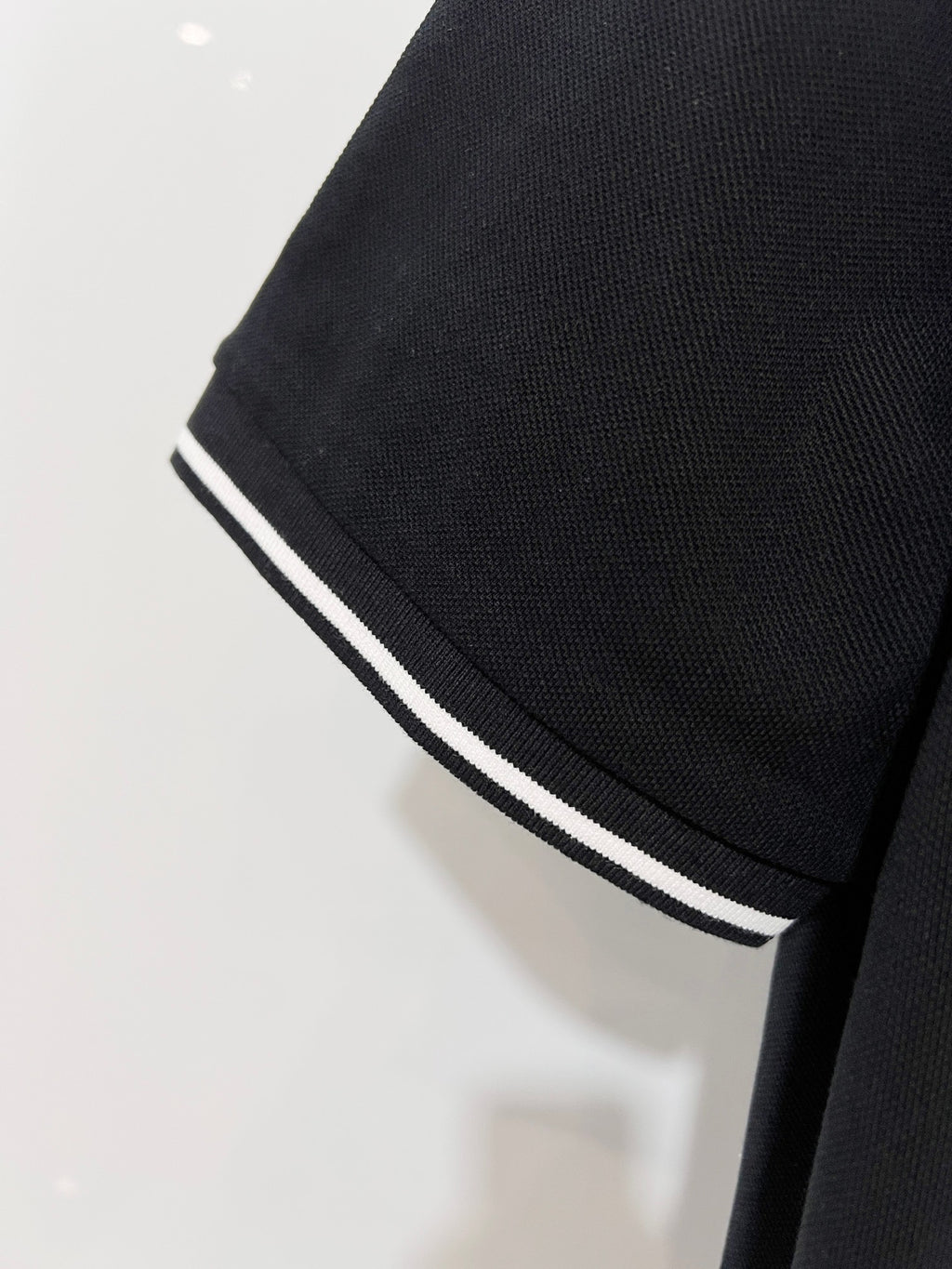 A polo shirt with embroidered letters on the eyes of a golden little monster on the chest