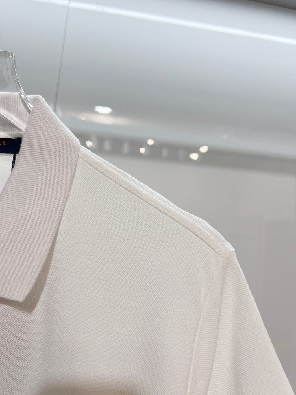 A polo shirt with embroidered letters on the eyes of a golden little monster on the chest