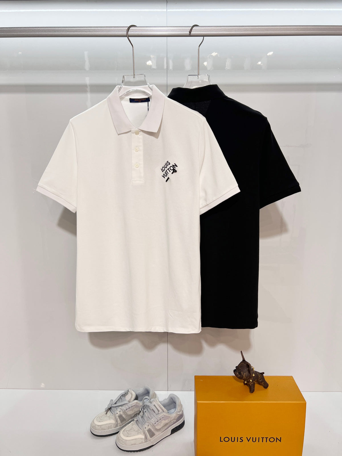 A polo shirt with embroidered letters on the eyes of a golden little monster on the chest