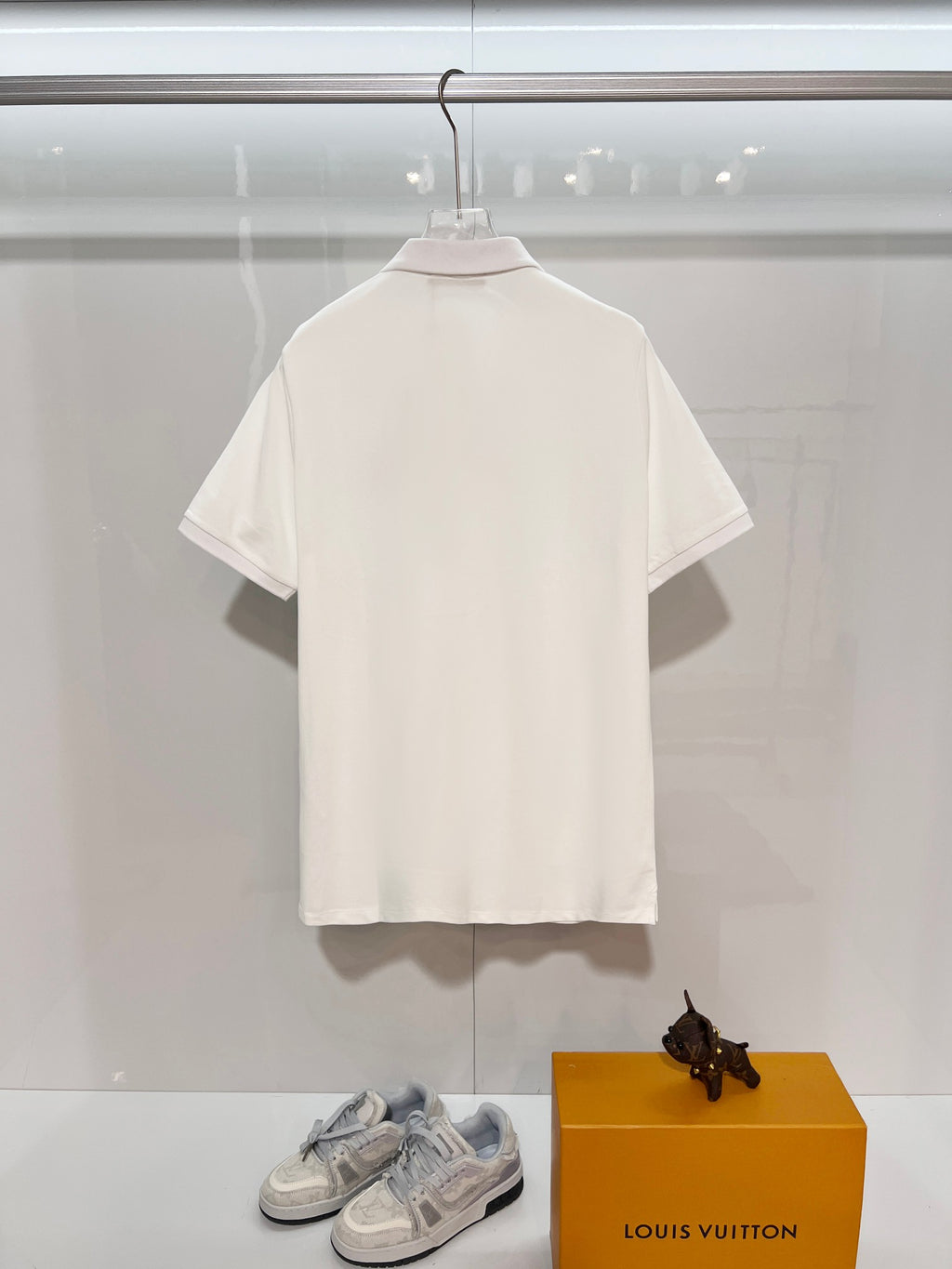 A polo shirt with embroidered letters on the eyes of a golden little monster on the chest