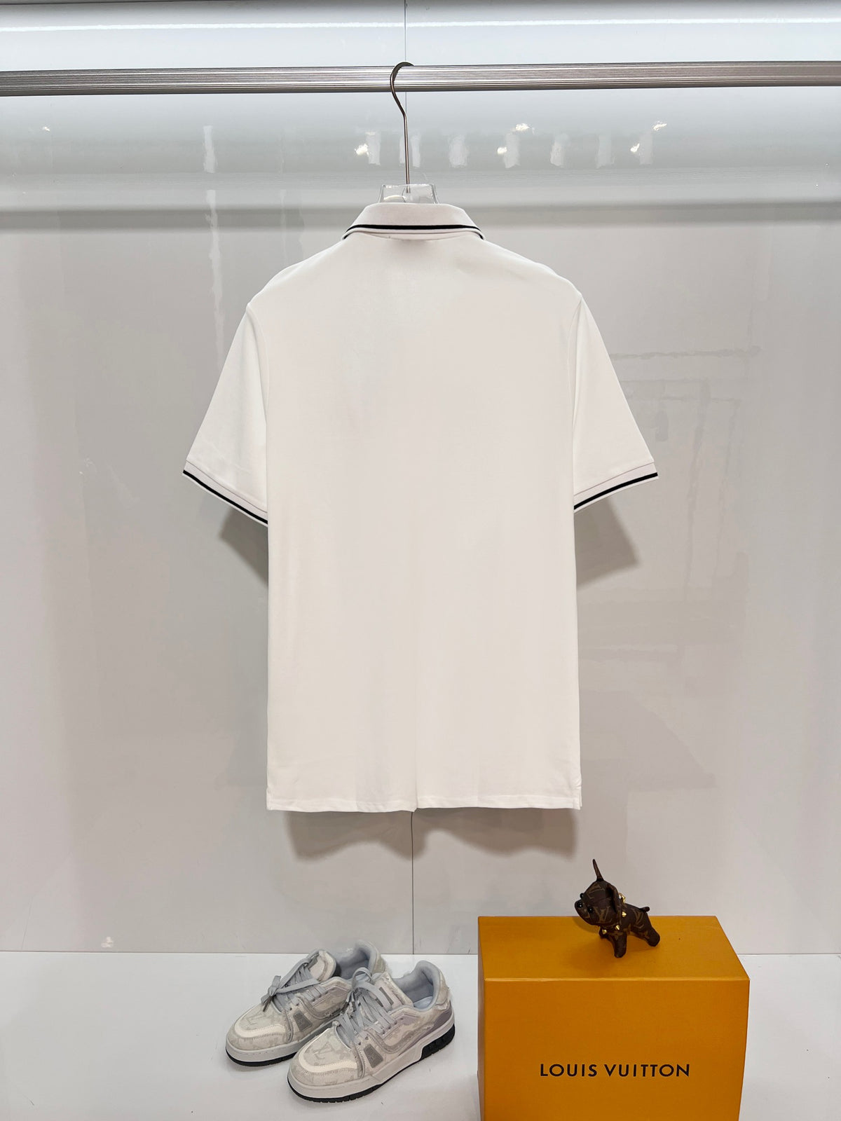 A polo shirt with embroidered letters on the eyes of a golden little monster on the chest