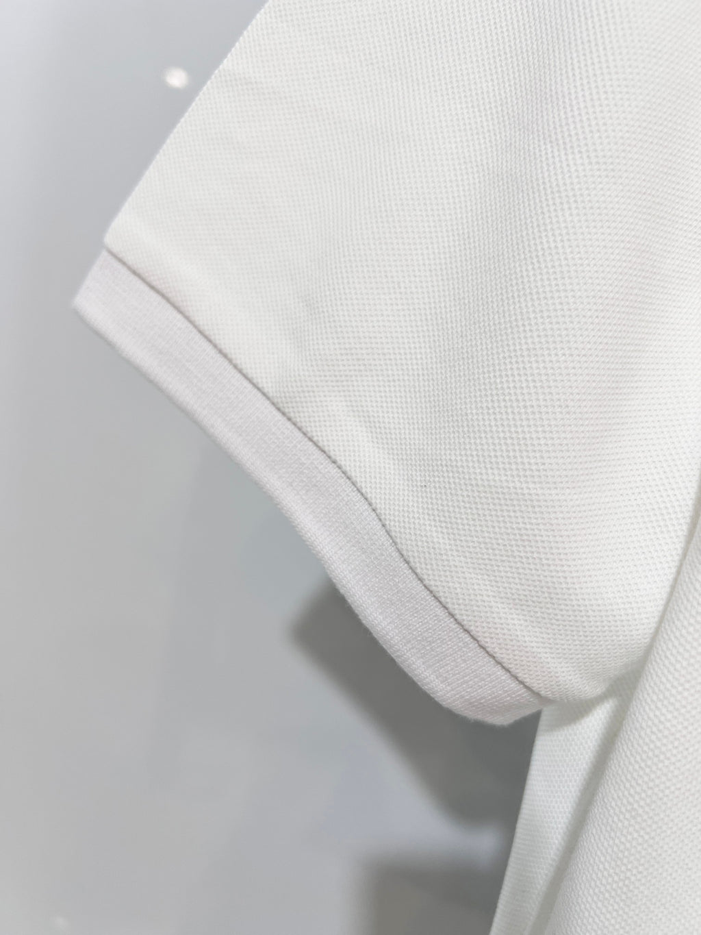 A polo shirt with embroidered letters on the eyes of a golden little monster on the chest