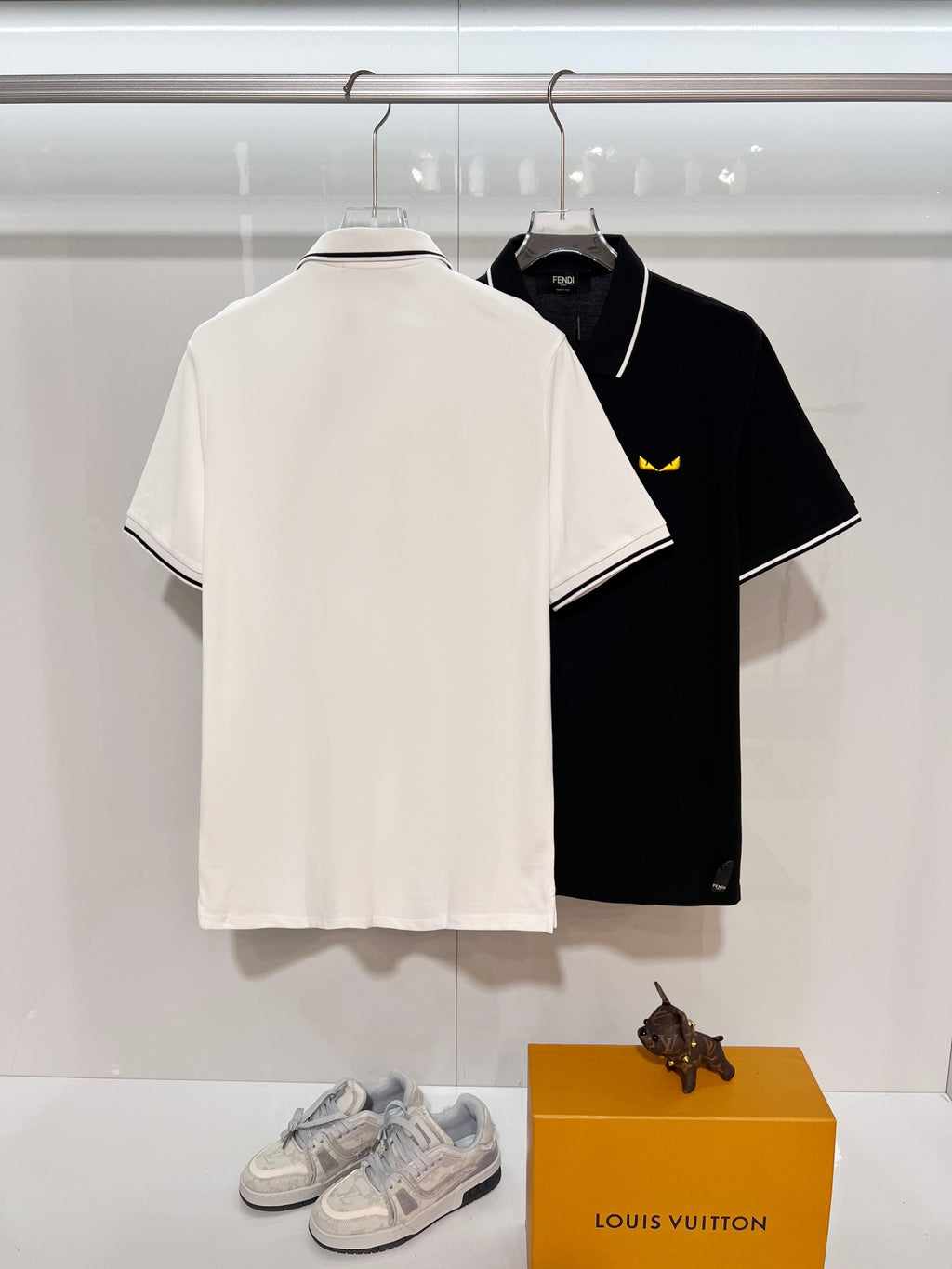 A polo shirt with embroidered letters on the eyes of a golden little monster on the chest