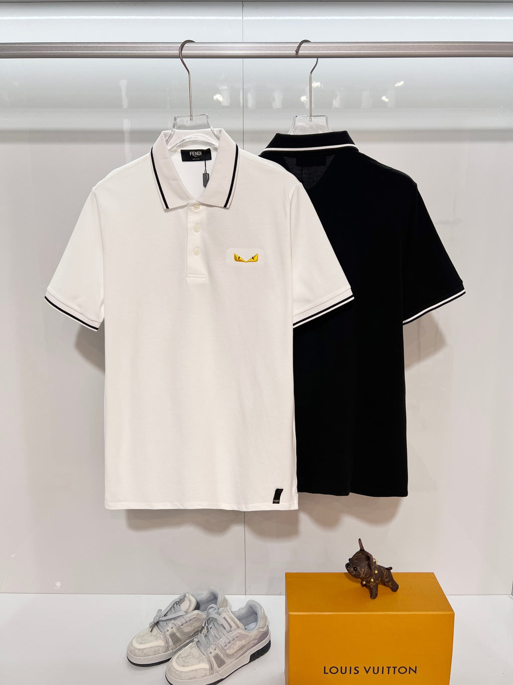 A polo shirt with embroidered letters on the eyes of a golden little monster on the chest