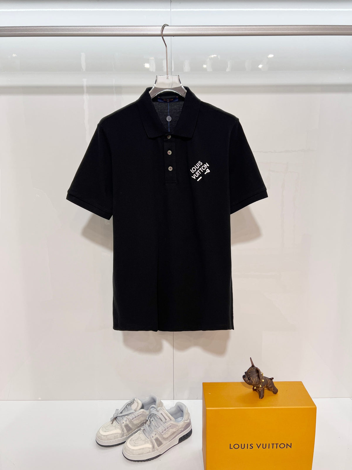 A polo shirt with embroidered letters on the eyes of a golden little monster on the chest