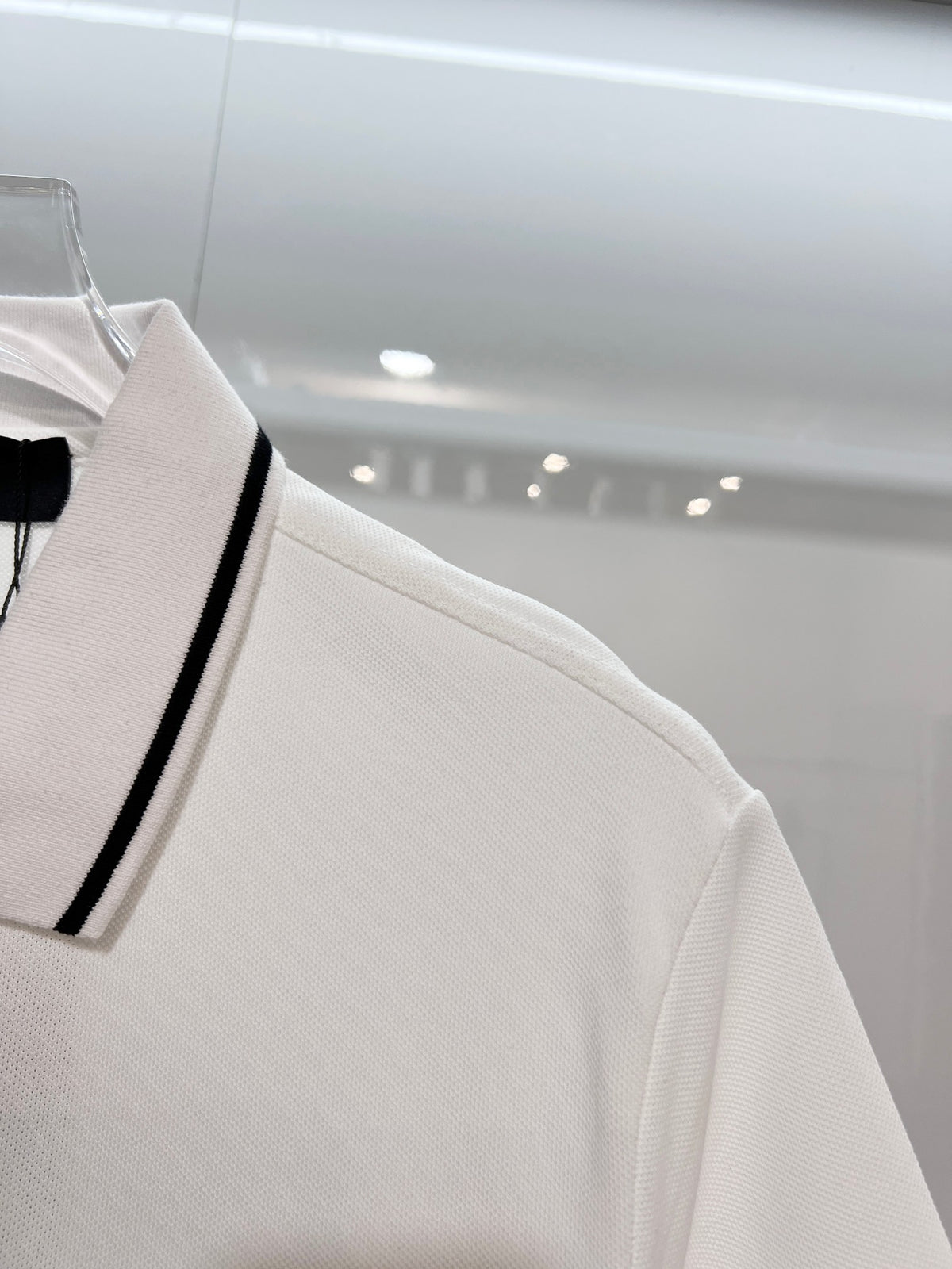 A polo shirt with embroidered letters on the eyes of a golden little monster on the chest