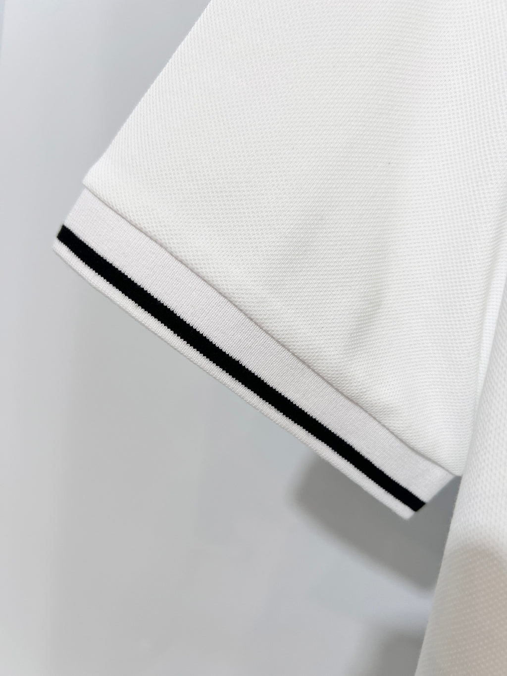 A polo shirt with embroidered letters on the eyes of a golden little monster on the chest