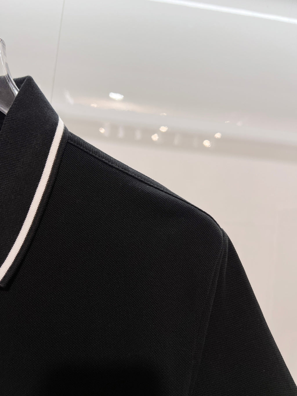 A polo shirt with embroidered letters on the eyes of a golden little monster on the chest