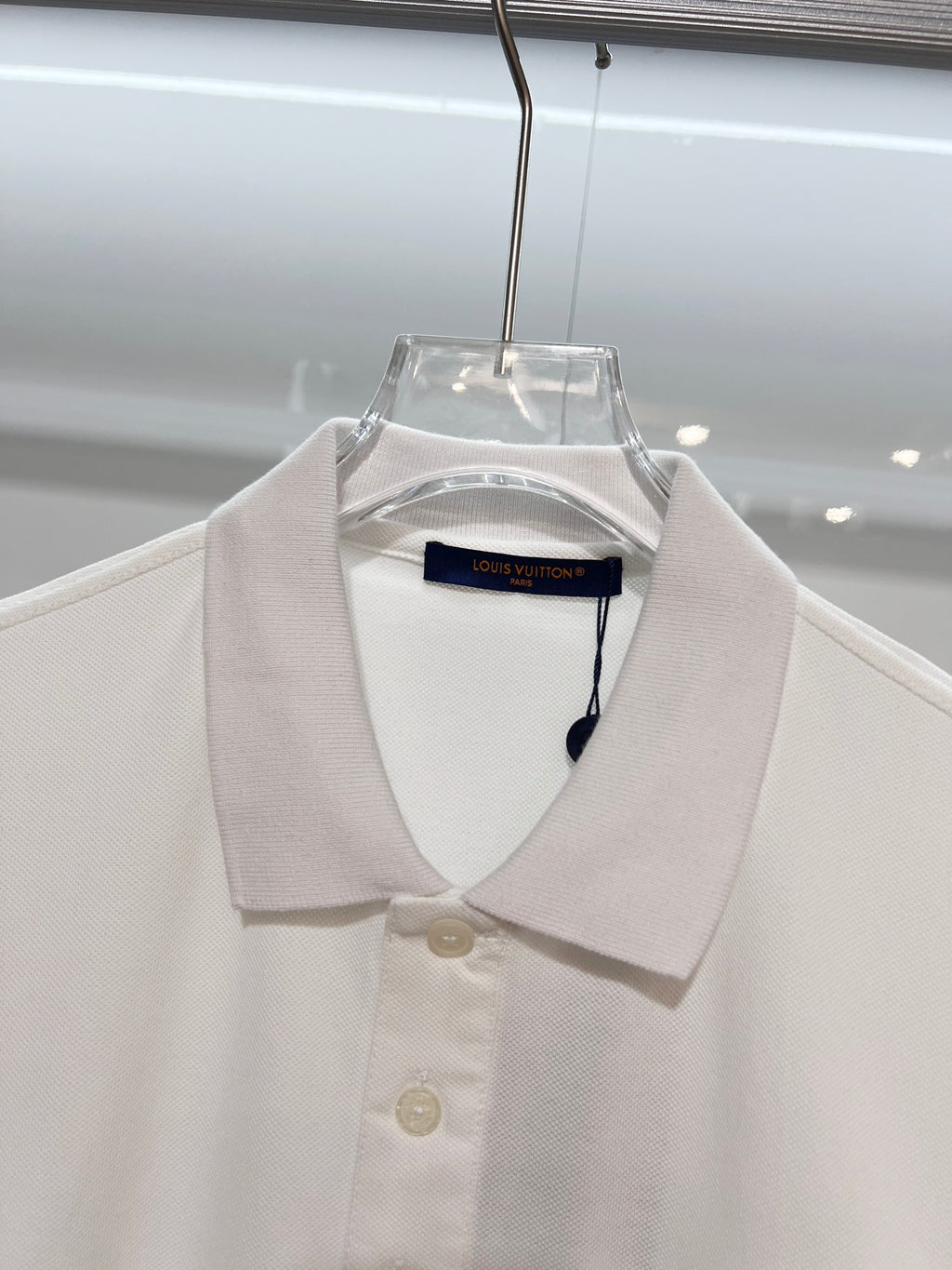 A polo shirt with embroidered letters on the eyes of a golden little monster on the chest