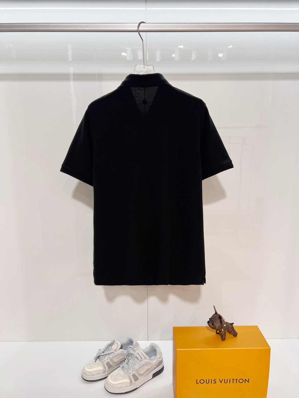 A polo shirt with embroidered letters on the eyes of a golden little monster on the chest