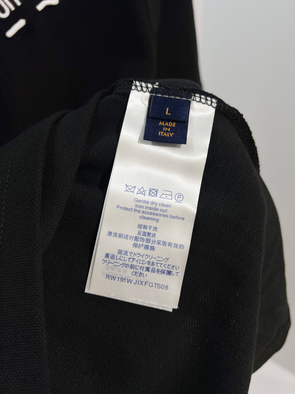A polo shirt with embroidered letters on the eyes of a golden little monster on the chest