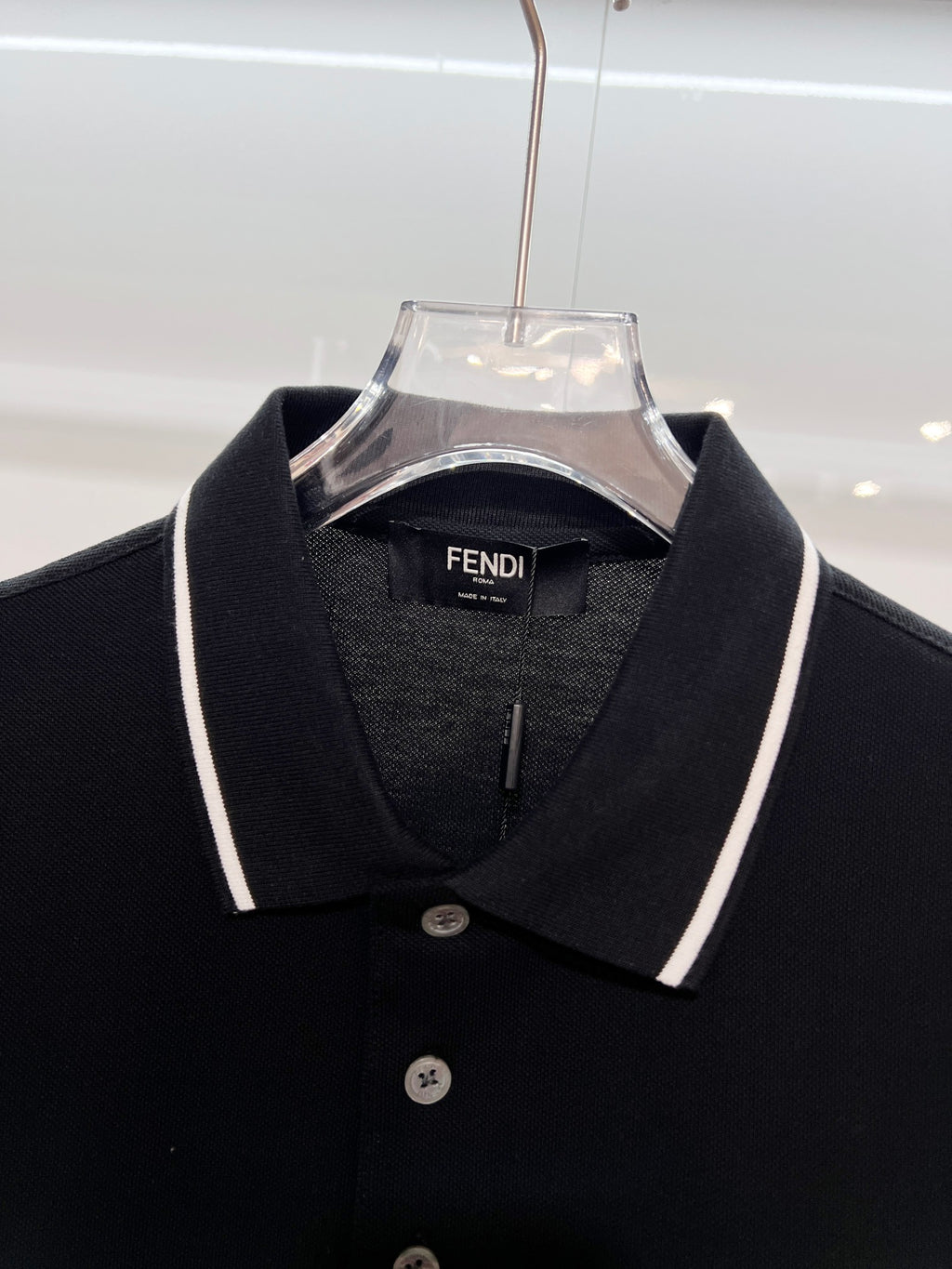 A polo shirt with embroidered letters on the eyes of a golden little monster on the chest