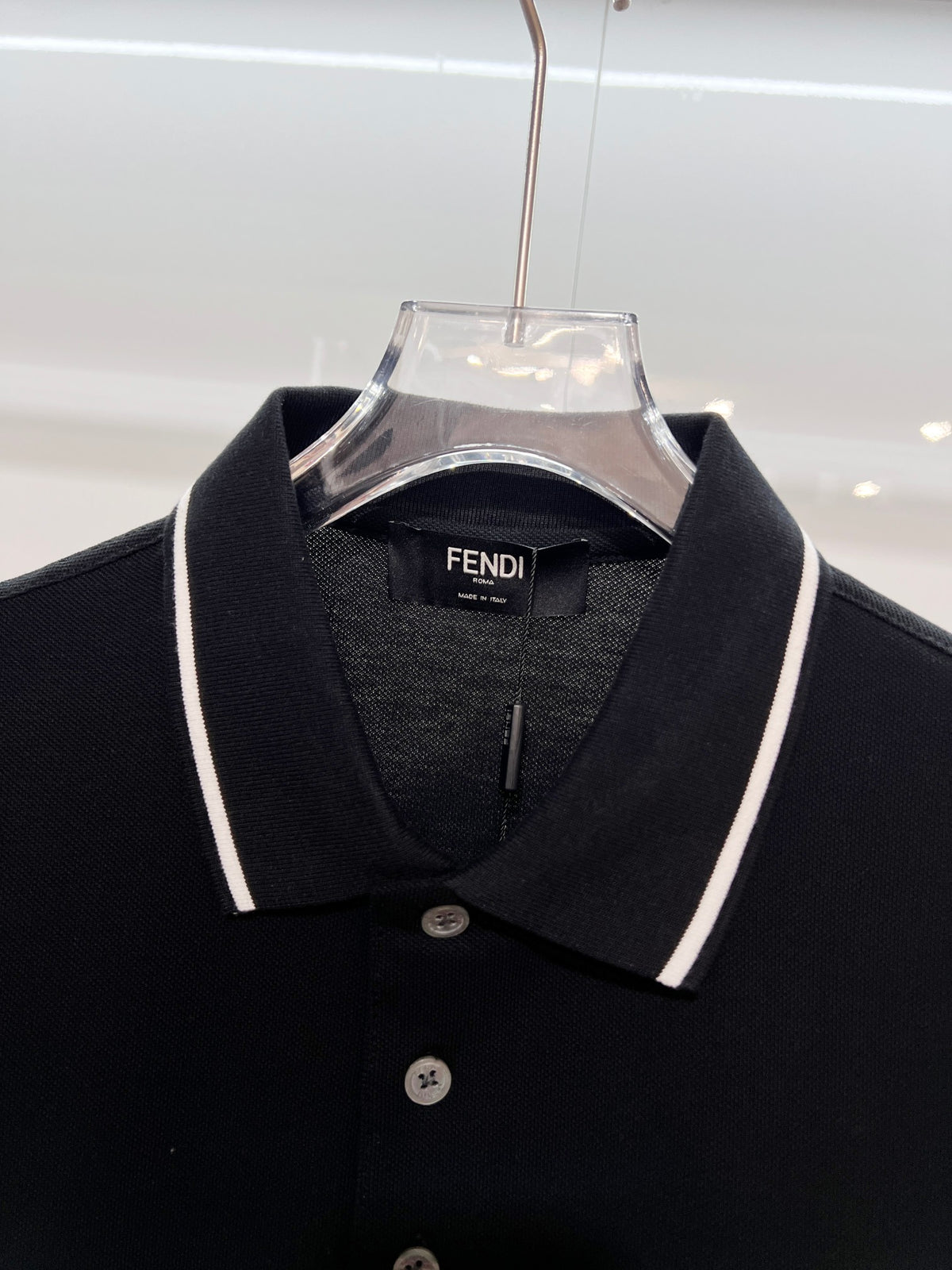 A polo shirt with embroidered letters on the eyes of a golden little monster on the chest
