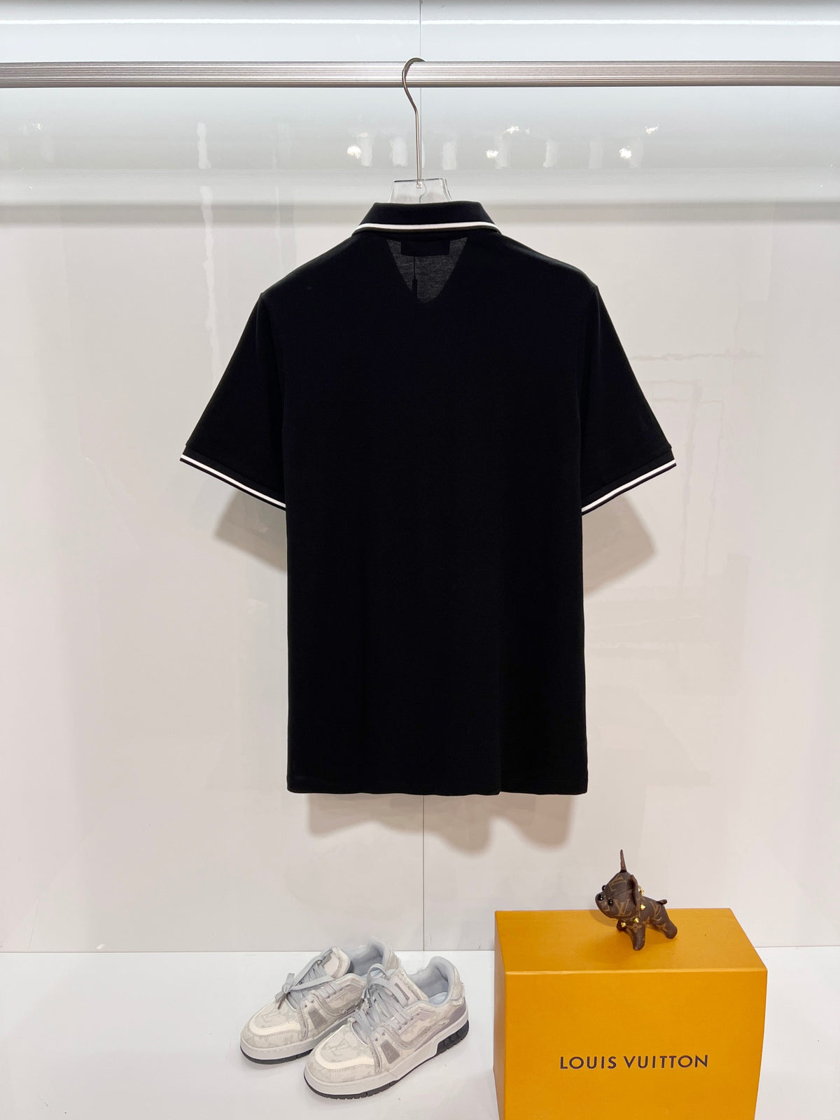 A polo shirt with embroidered letters on the eyes of a golden little monster on the chest