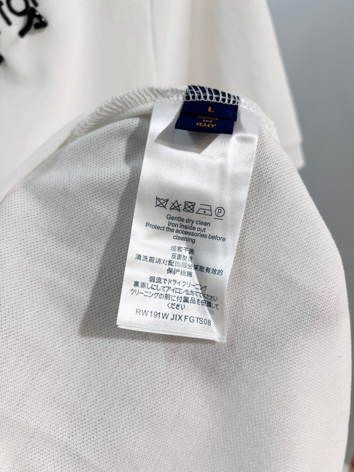 A polo shirt with embroidered letters on the eyes of a golden little monster on the chest