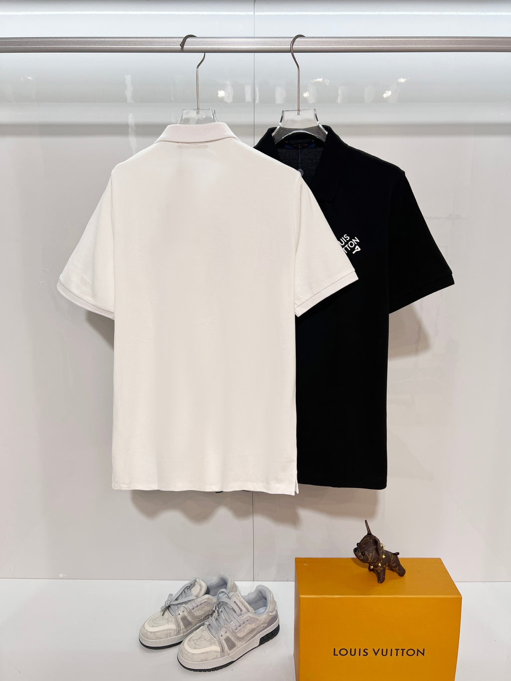 A polo shirt with embroidered letters on the eyes of a golden little monster on the chest